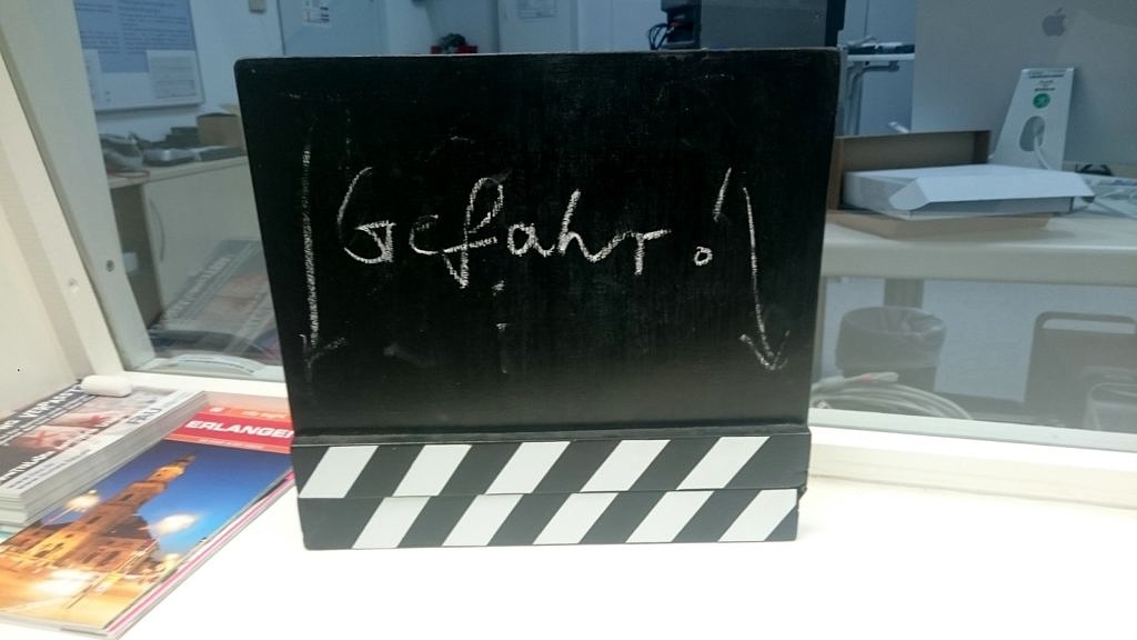 Foto von einer Tafel aus Filmaufnahmen, auf der das Wort Gefahr steht